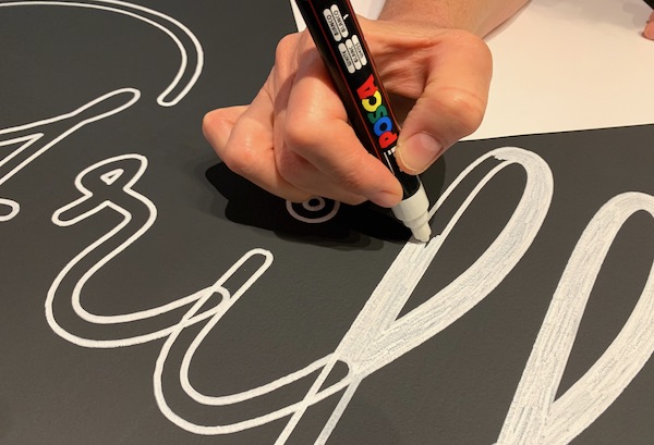 The artist hand-paints inside the outlines after the drawing robot lettering.